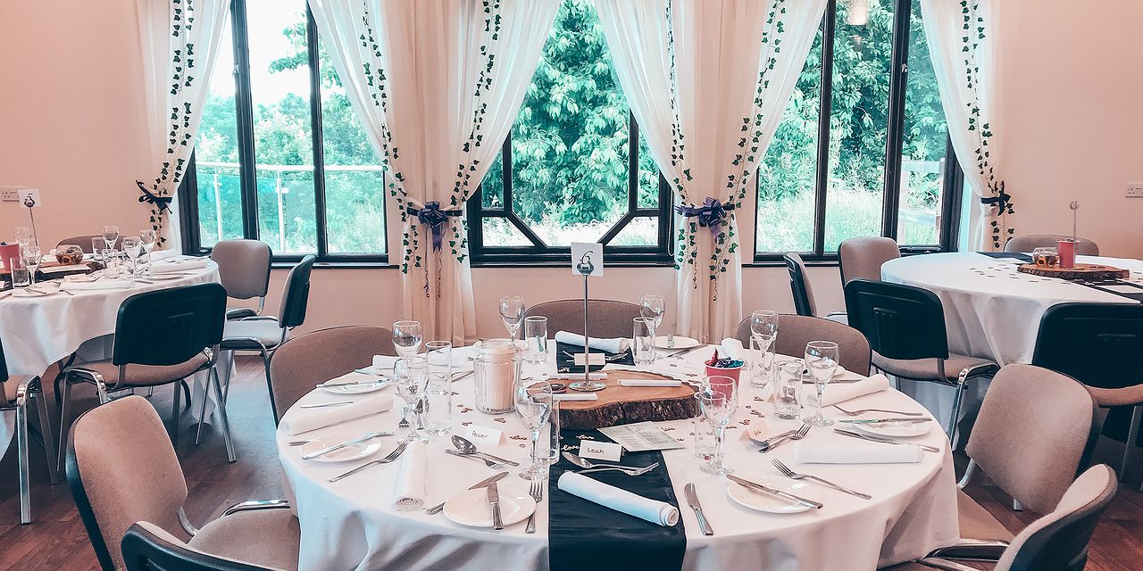 Round tables set up for a meal with white curtains and table cloths.